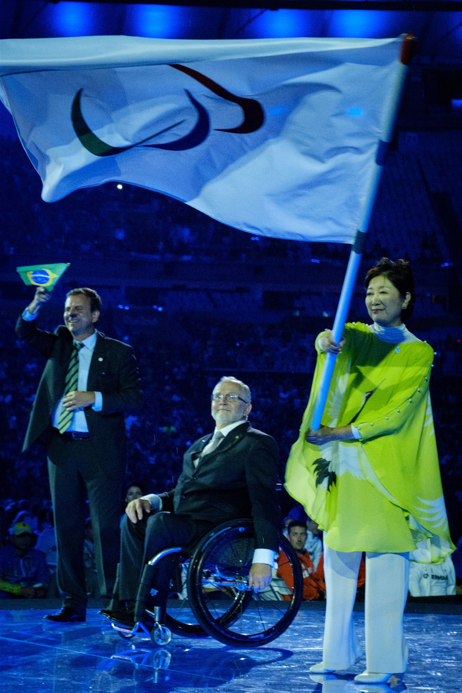 下届残奥会东道主日本代表、东京市长小池百合子（右）挥舞著五环旗；左起为里约市长帕埃斯以及国际残奥委会会长克雷文。