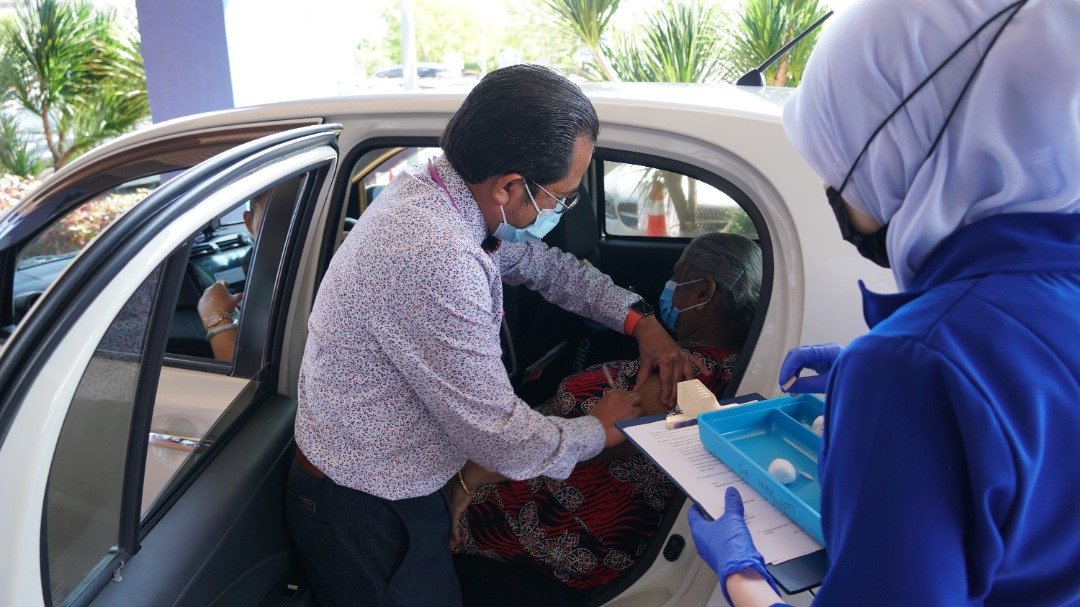 仄万阿米鲁医生（左）为在车内的民众接种疫苗。图取自巴西古当KPJ专科医院面子书
