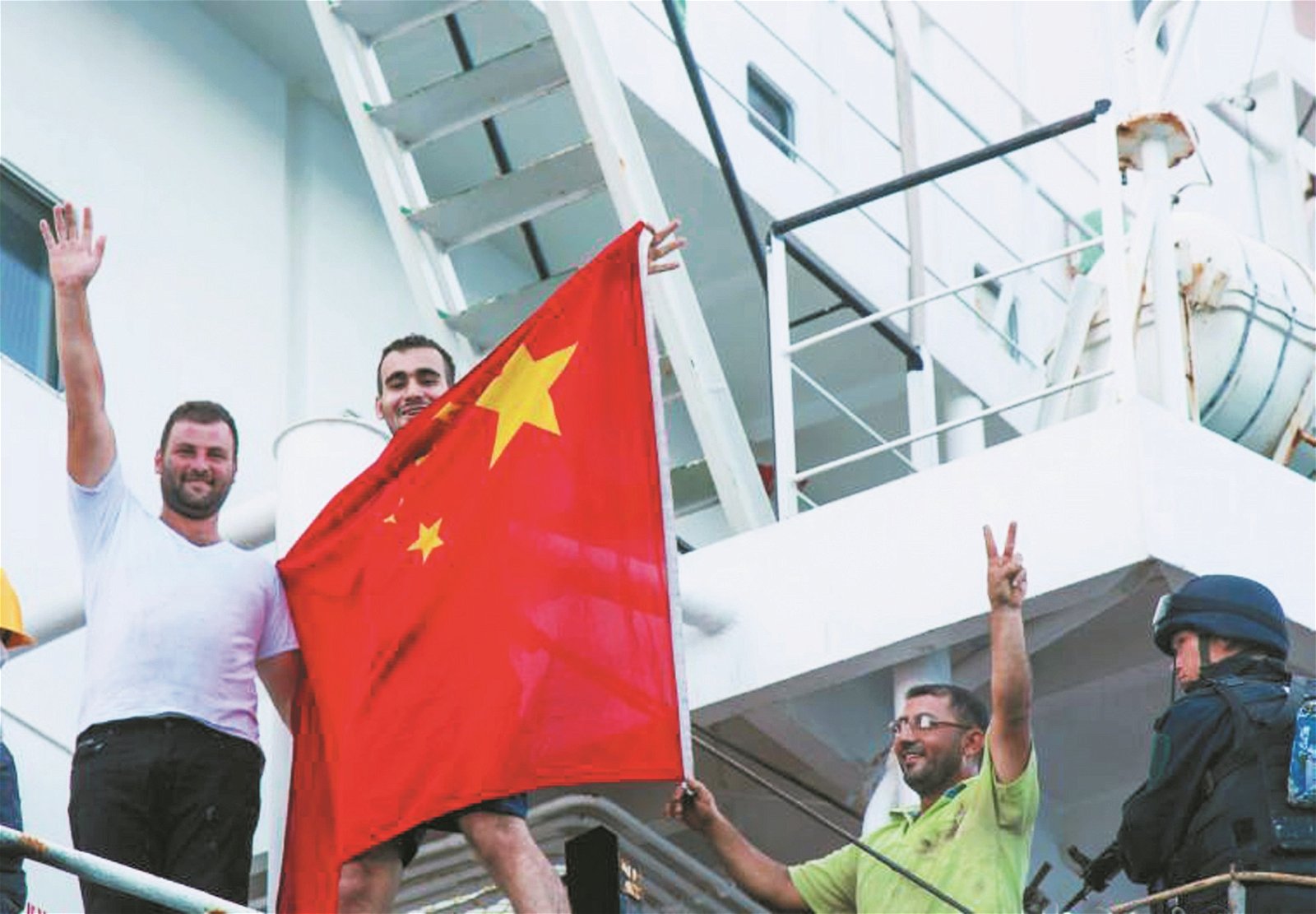 安全到达目的地后，货船船员举起中国五星红旗，送别随船护卫的9名中国护航官兵。