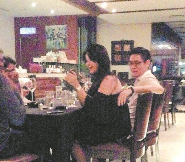 貌似再里尔的男士，与一名性感打扮的女郎并排坐在一家高级餐厅里。