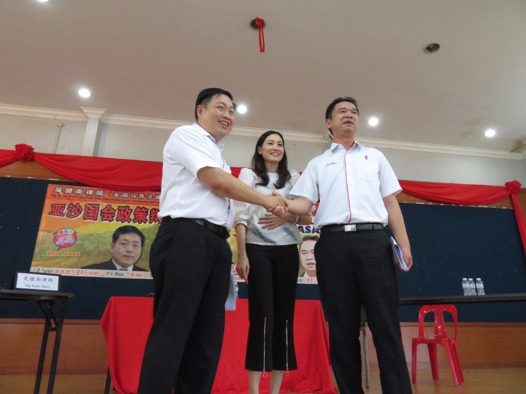 “吴张辩”结束后，吴健南（左）及张聒翔（右）互相握手。中为主持人李晓蕙。