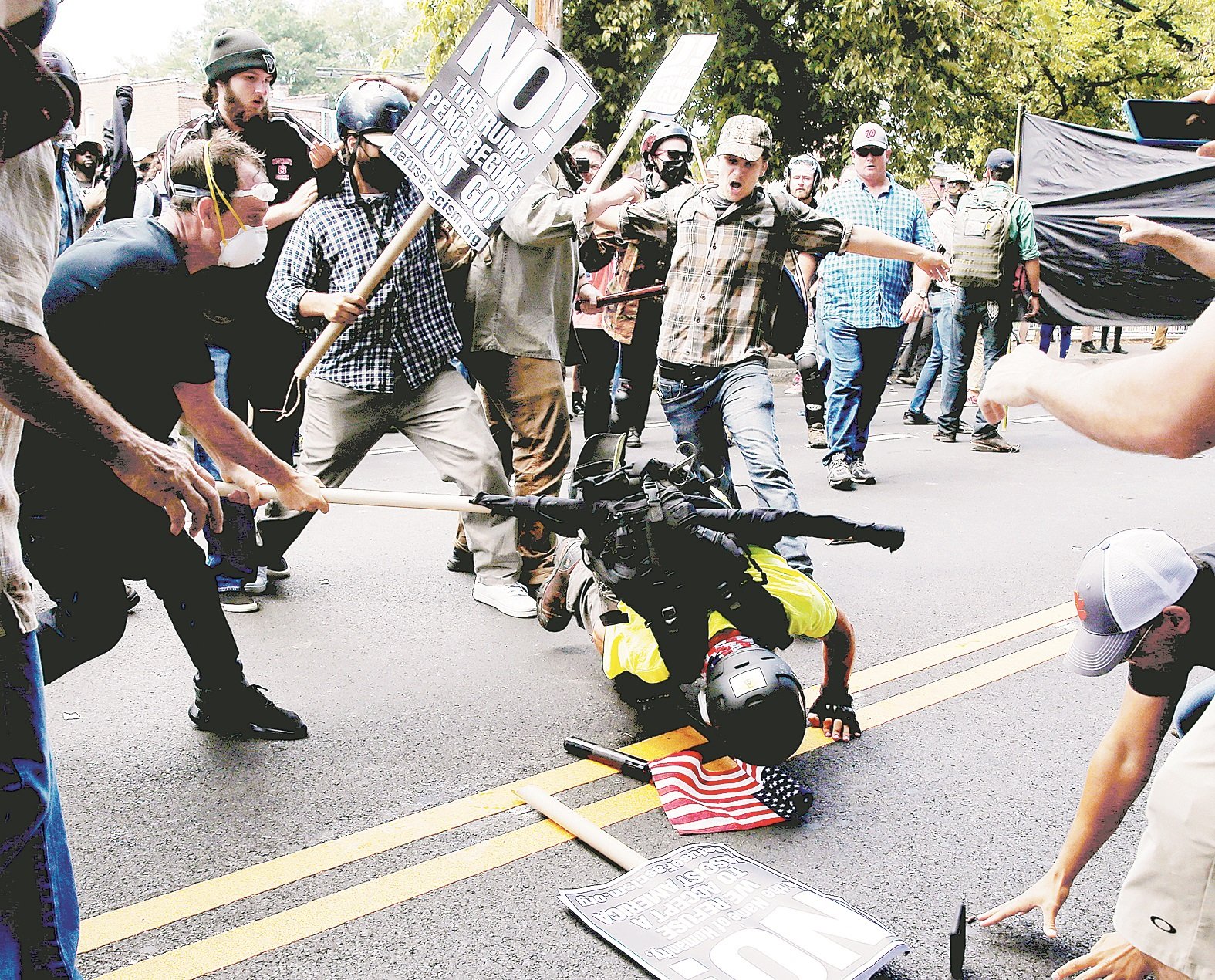 一群反对白人至上示威的人士，将一名手持美国国旗的白人优越主义示威者，强行压制在地上，场面火爆。