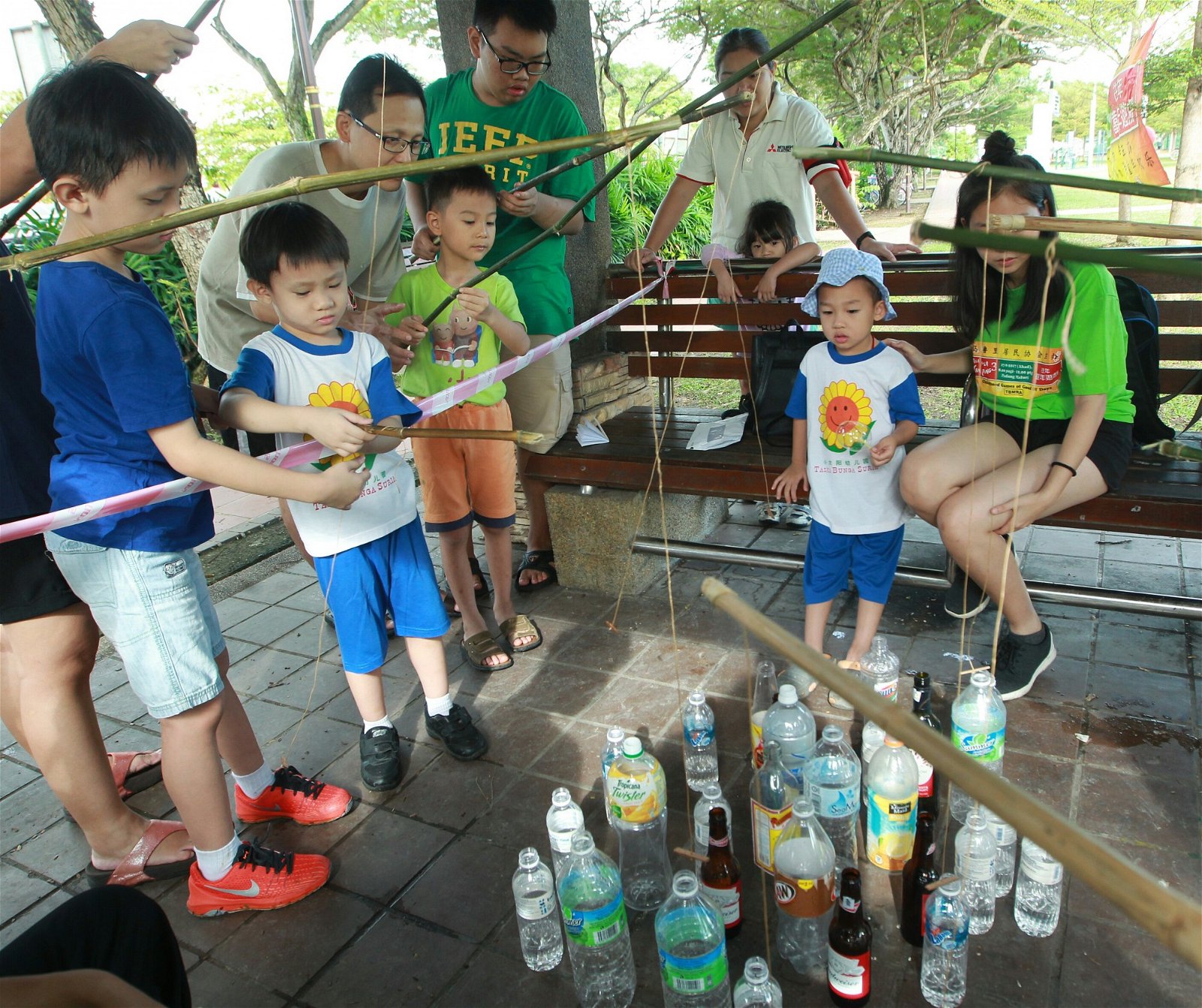 “钓玻璃樽”游戏吸引大批父母及小孩捧场，小孩全神贯注地将“钓竿”中的木块慢慢放入玻璃樽里，再用木块支撑瓶口，一把将水瓶拉起。