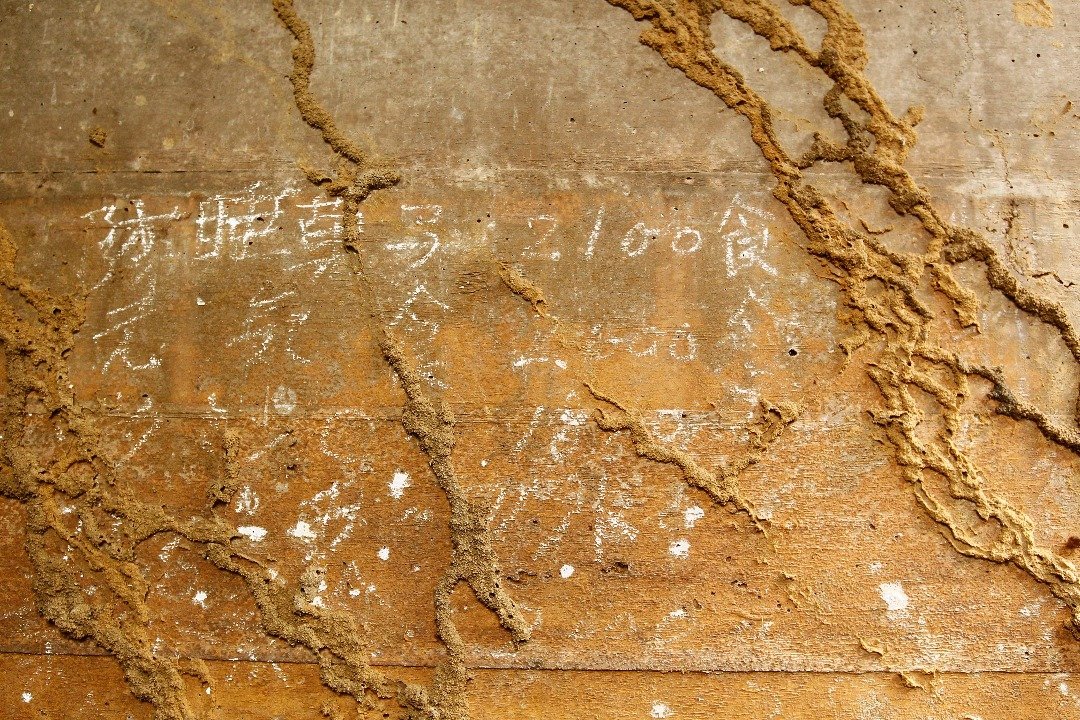 防空洞内的墙壁上写有中文字，但仅剩下小部分的字隐约可见，大部分的字已消失。