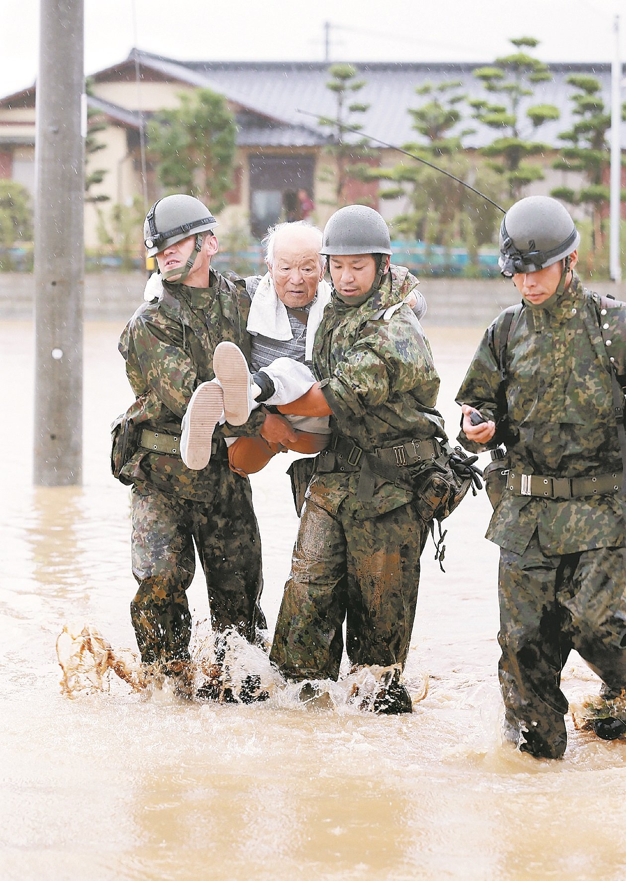 周四在朝仓市参与救援的自卫队成员，合力抬起一名行动不便的老人，撤离到安全地区。