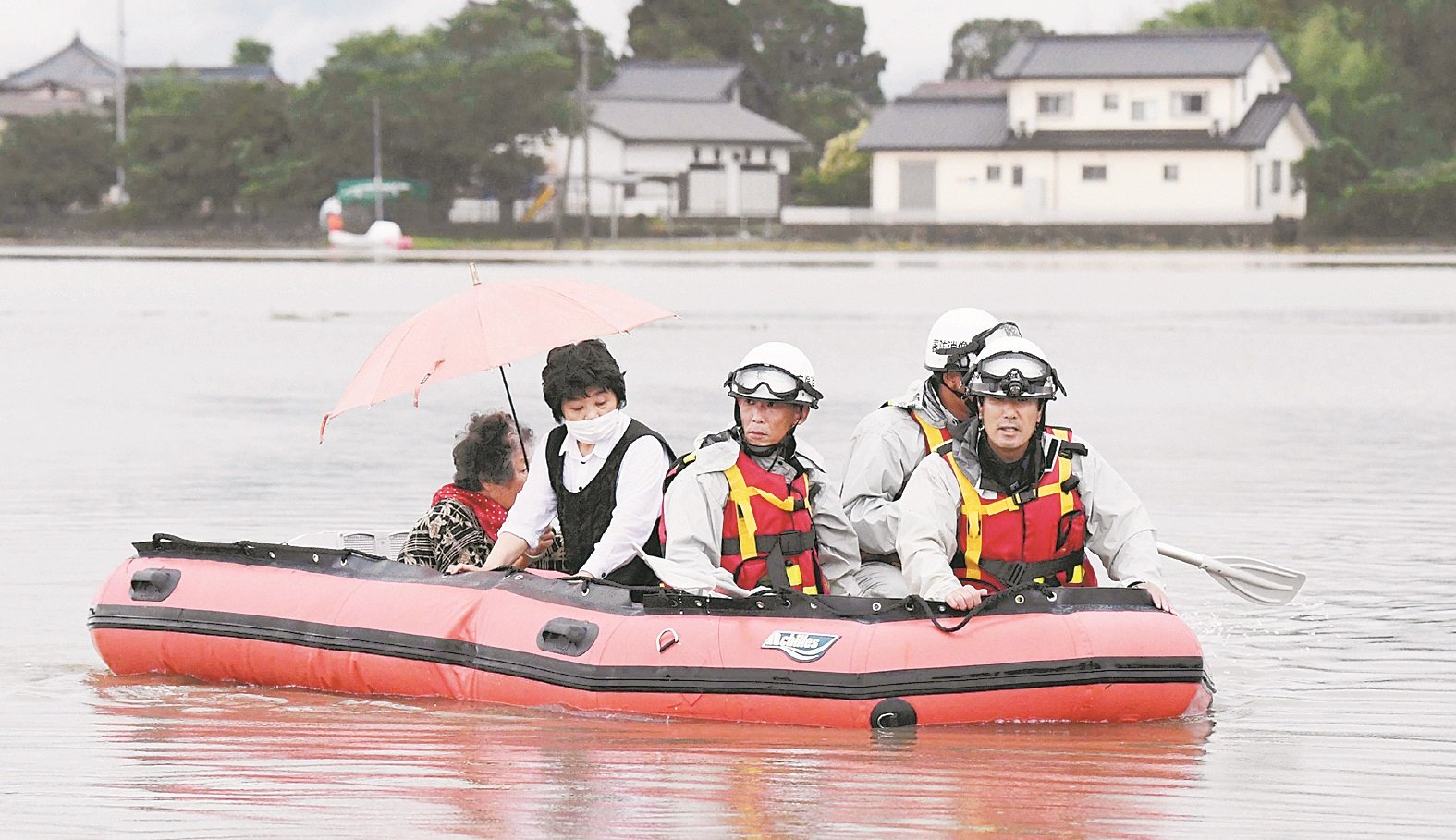 九州暴雨成灾，福冈县朝仓市受灾严重，消防人员用橡胶艇，载送居民离开被淹的家园。
