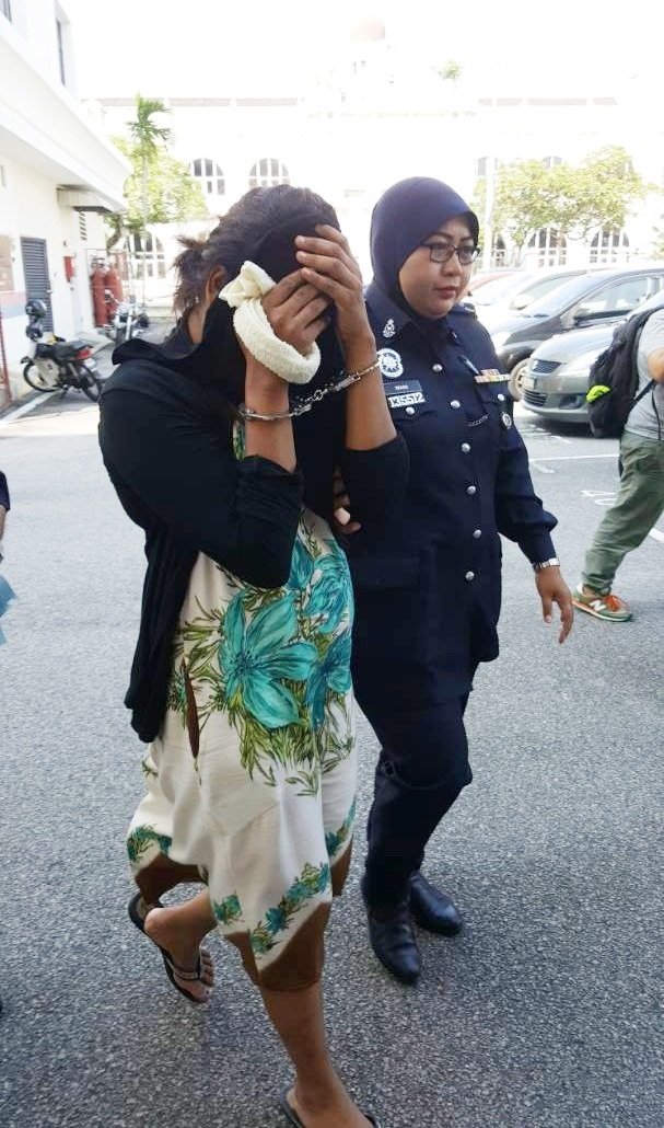 女被告（左）周四在槟城法庭分别面对谋杀罪及吸毒罪，在庭外用黑色外套遮脸。