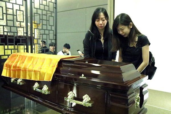 林知麟的大姐林舒闲（左）与二姐林舒菁在弟弟的棺木前，哭成泪人。