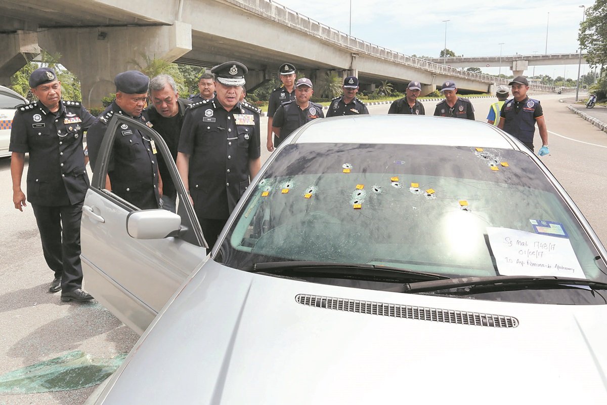 万阿末（前排左3）向查案的警方人员，了解3名乘坐著豪华宝马轿车的男子犯案的情况；轿车档风镜可见15个弹孔。