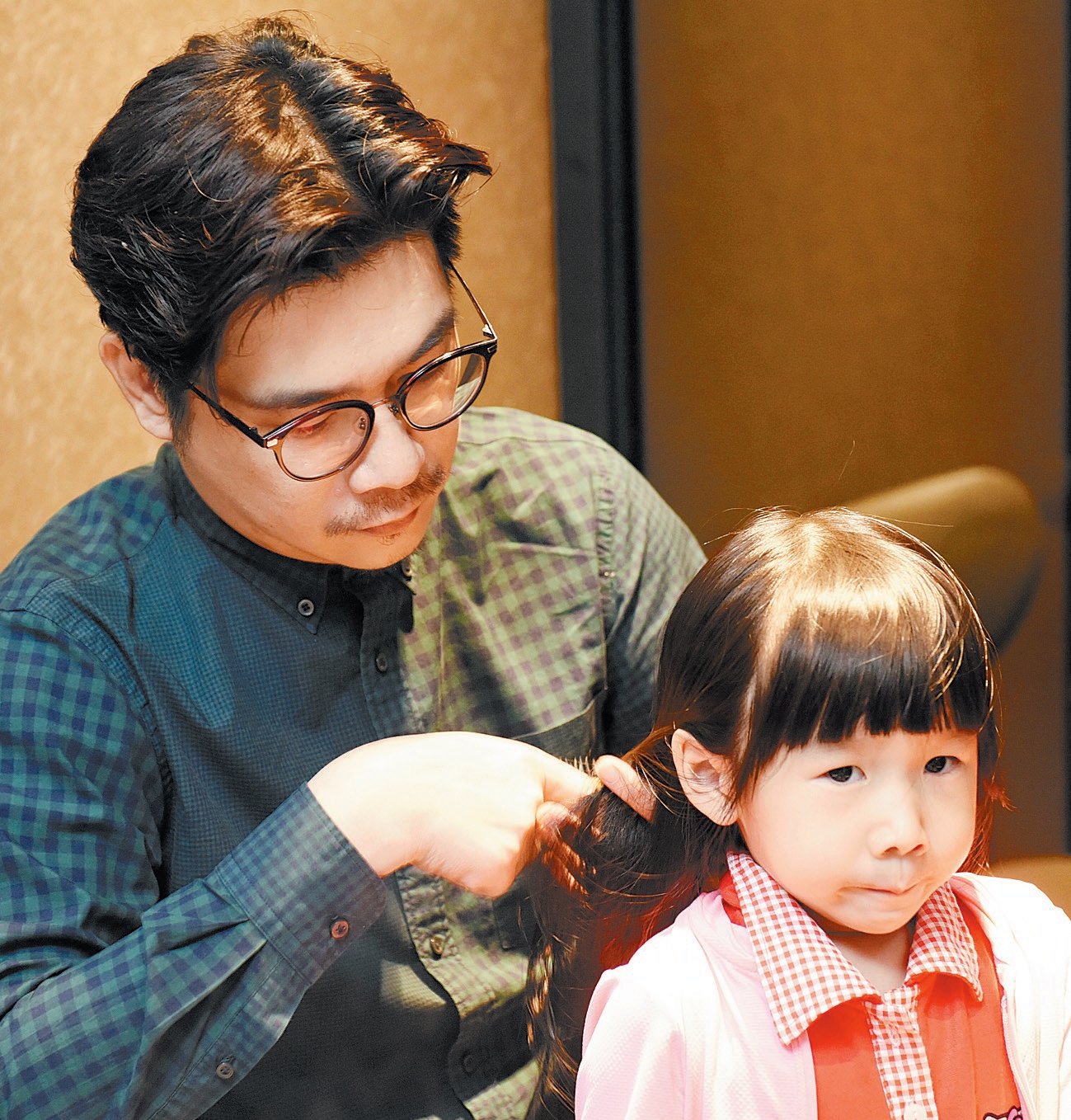 为女儿梳理头发的黄威尔，看得出他是体贴的爸爸。（摄影：黄良儒）