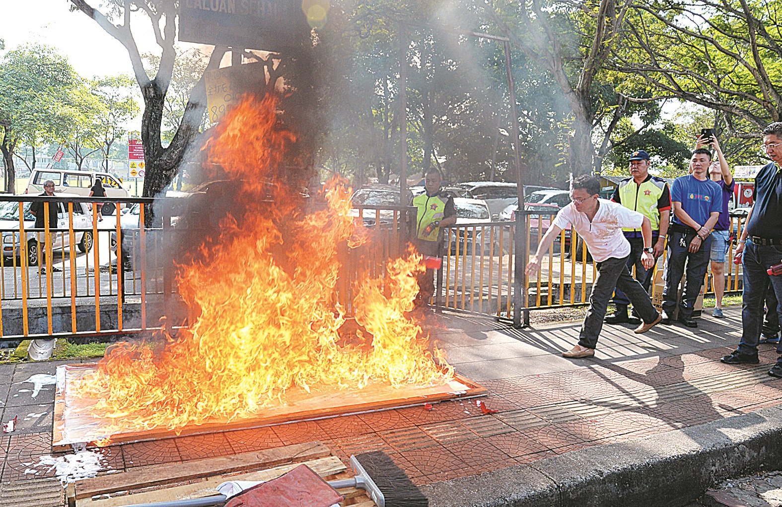 王胜龙（左）在示范如何把新型灭火器投掷到火里，以达到灭火的效果。（摄影：曾钲勤）
