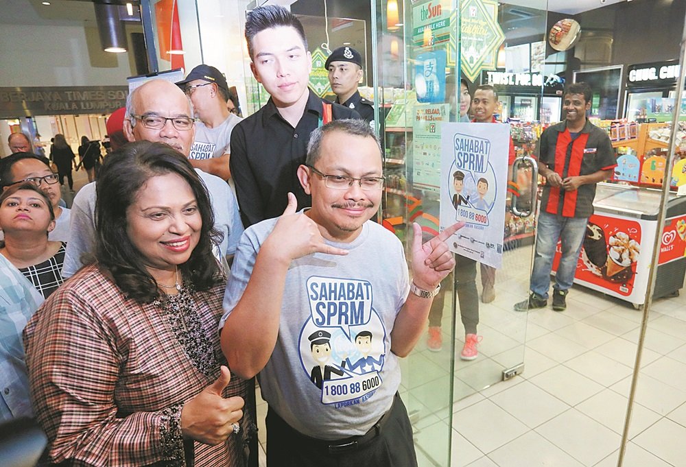 马来西亚成功集团执行董事拿督祖莱纳（前排左起）与祖基菲里，共同推介“反贪会之友”，祖基菲里更比出拨电话的手势，呼吁大众踊跃联络反贪会揭发贪污。（摄影：骆曼）