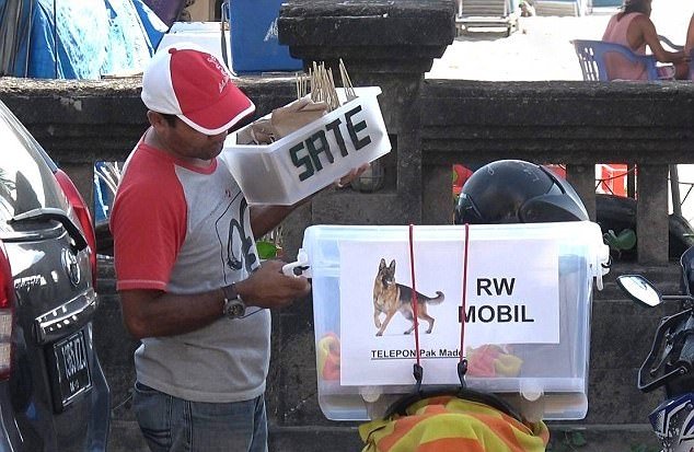 巴厘岛小贩从摩哆的箱子取出狗肉串，到水明漾的沙滩向游客兜售。