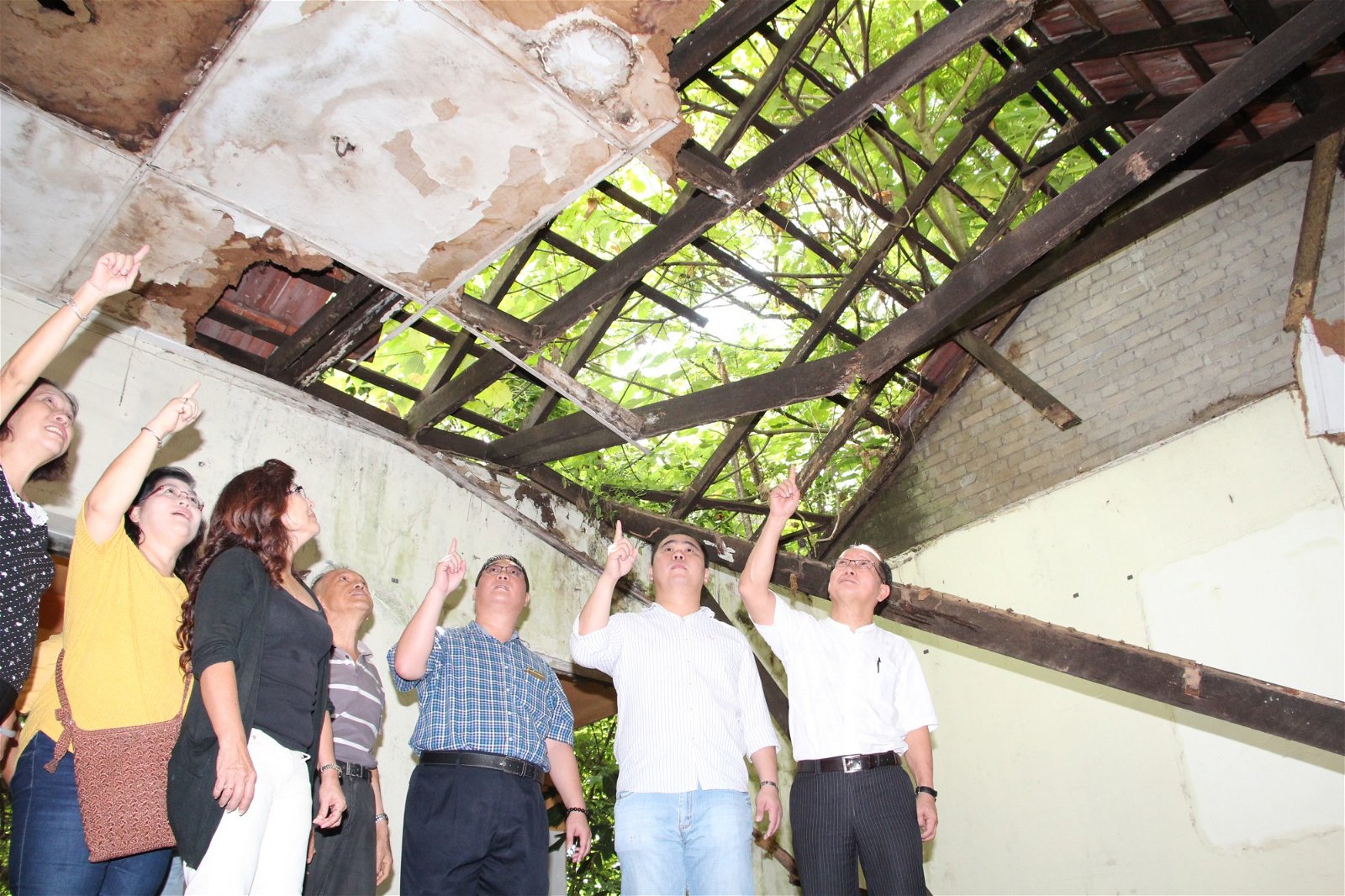 魏木荣（ 右） 的带领吴瑞英（ 左3 ） 和尤沈峻（ 左5 ） 等人，巡视废置9年的大山脚官员宿舍，屋顶破不成形。