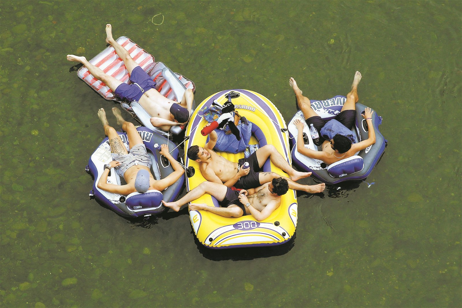 【瑞士】苏黎士的利马特河中，青少年们悠闲地躺在游泳圈和漂浮气垫床上，喝著冷饮消暑。