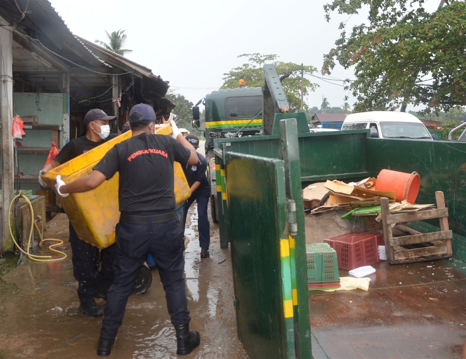 执法人员合力把充公物品，搬上当局准备大型垃圾槽。
