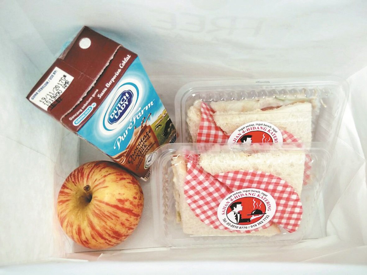 餐车免费派发的营养早餐，包括三文治、苹果和牛奶。