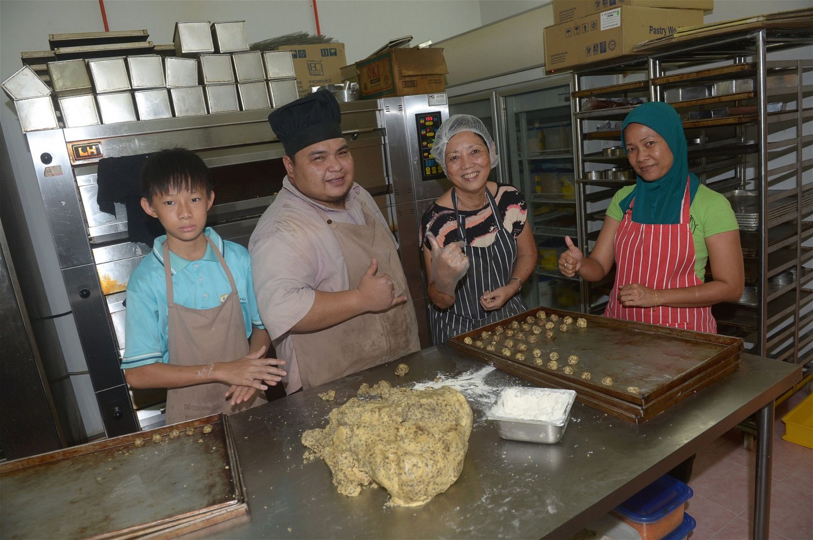 在面包师傅（左2）的培训下，程雪玲熟练烘培面包的每一步骤，也享受烘培的乐趣。（摄影：陈启新）