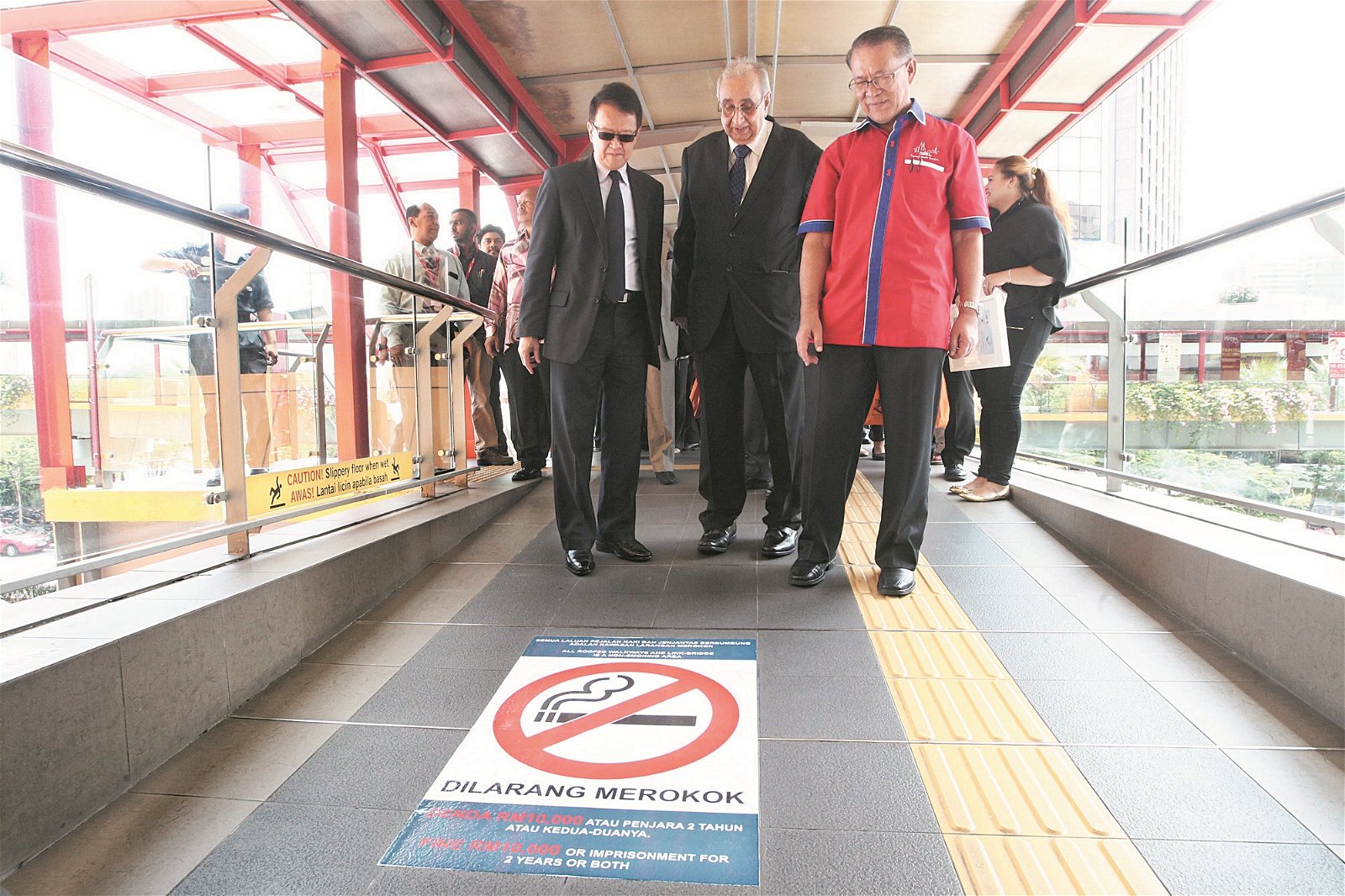 被吉隆坡市政局列为禁烟区的地点，都会贴上禁烟标志，一旦违规，将面对法律责任。阿敏诺丁（左3）巡视被列为禁烟区的双威布特拉太子购物广场的有盖人行道。左起为谢富年及乐卡佳。（摄影：伍信隆）