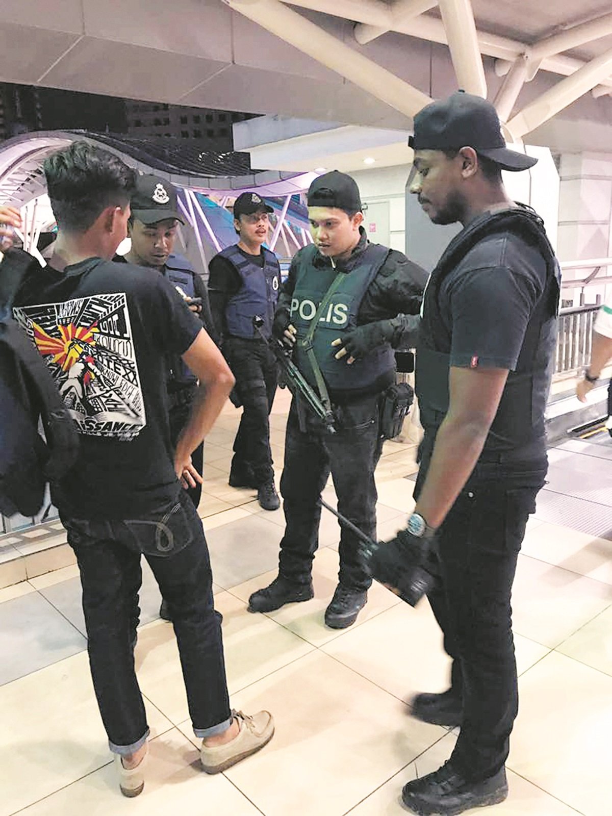 警方人员在商场中盘问可疑民众。