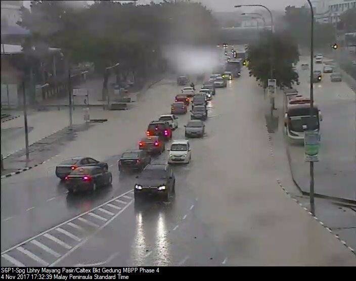 槟岛西南区玛央巴锡路路面淹水，经过的车辆只好放慢速度，导致当地交通拥堵。（图取自槟岛市政厅面子书）