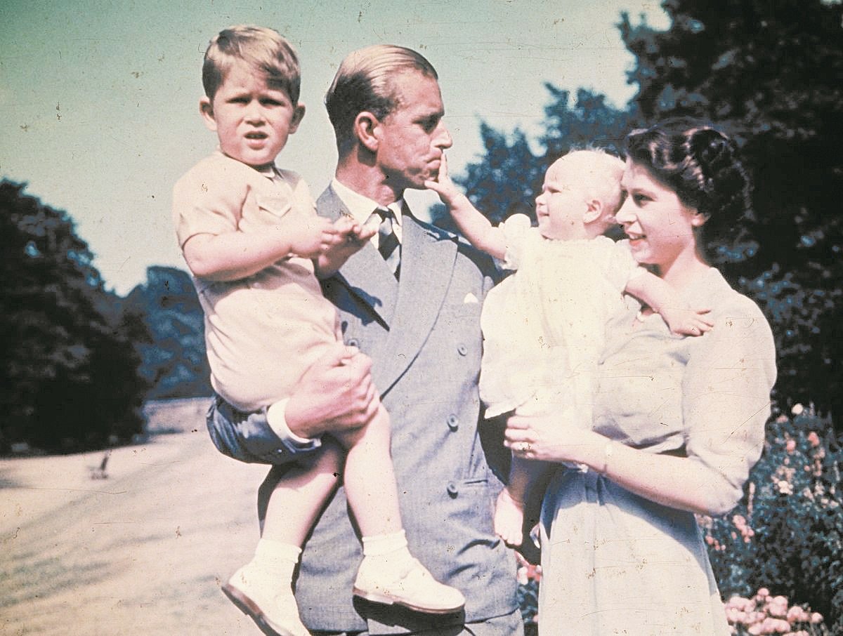 伊丽莎白二世女王和菲利普亲王，1951年8月在官邸克拉伦斯府拍生活照。他们分别抱著长子查尔斯王子（左）和安妮公主，当时快要满周岁的安妮公主，调皮地用手按住父亲的嘴巴，菲利普则是任由爱女摆布，紧闭嘴巴慈祥地看著安妮公主。