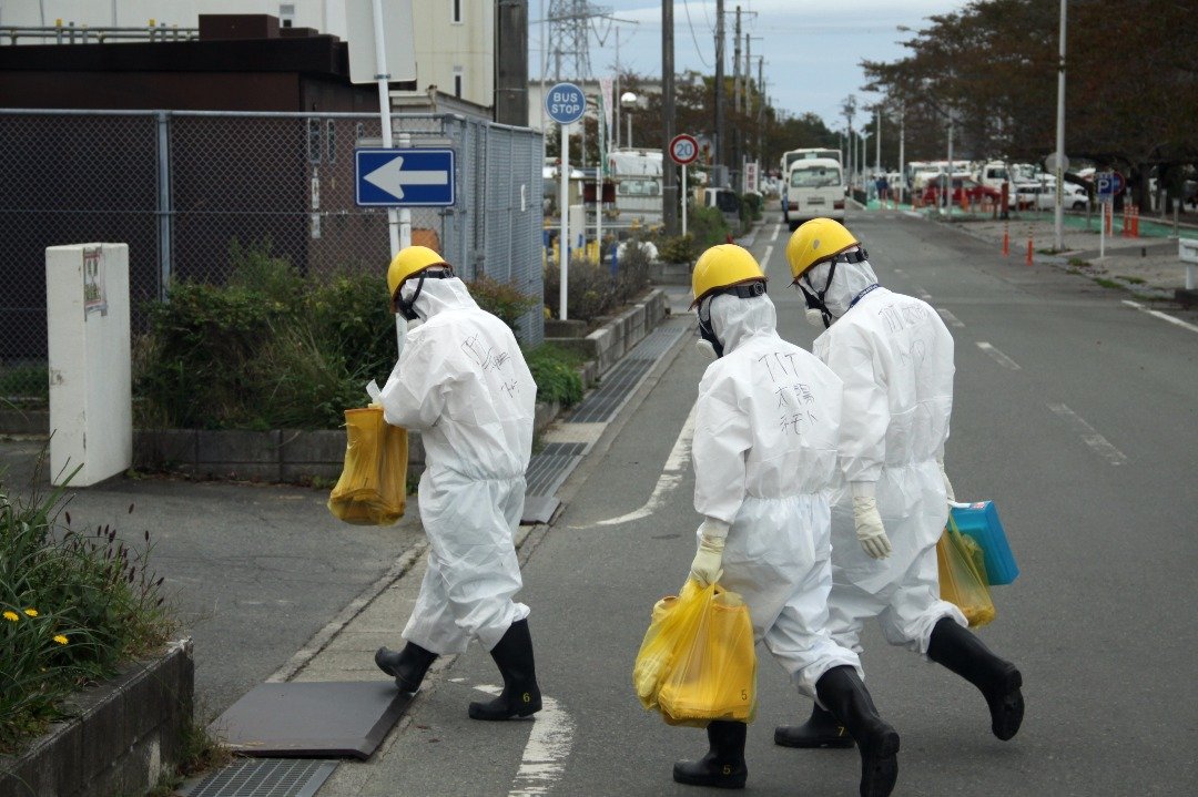 身著全副防护装备的施工人员，进入福岛第一核电厂。在核厂内工作，暴露在高辐射中，必须做好准备，从头到脚都需要核防护服保护。