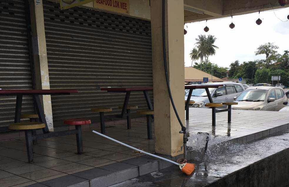 甘榜峇鲁巴刹店铺外的水表被盗后，大量的水往外溢出。