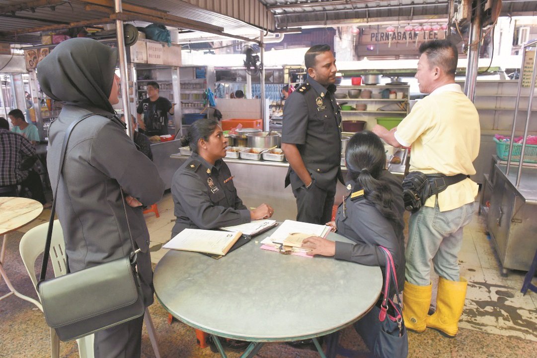槟州贸消局4名官员向杂饭档主“阿枫”（右）了解情况，并促他尽快张挂饭菜价格表。