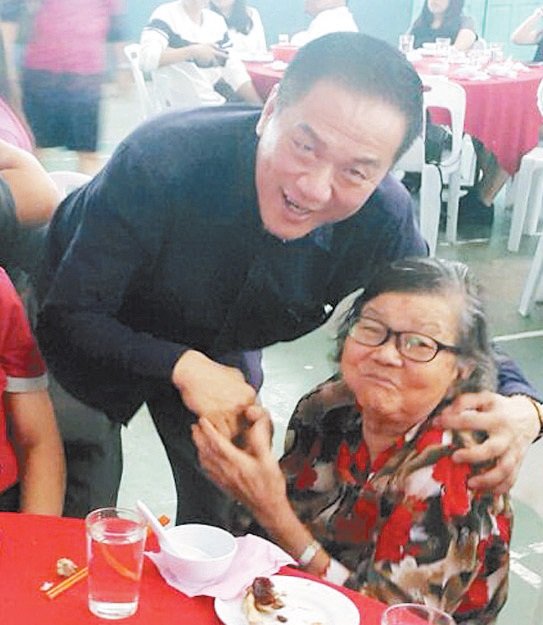 来自民政党的陈国祥（左）在一项亲民活动中，拥抱一名婆婆级选民。