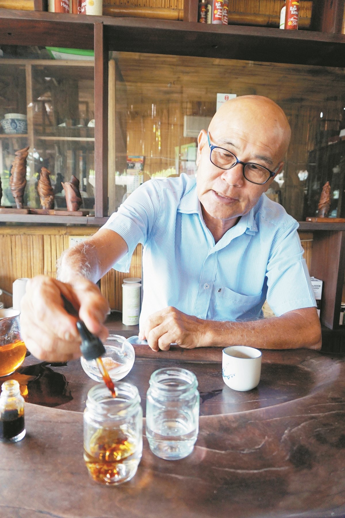蔡日昇用碘酒测试自 来水（左）和帝王木茶 的水性（右），以证明 帝王木如何解毒。