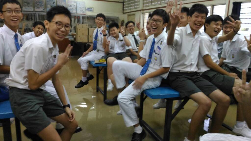 灾水灌入槟城钟灵中学部分课室，一些学生坐在桌子上“逃难”，但看学生们的神情，仿佛还懂得“苦中作乐”。