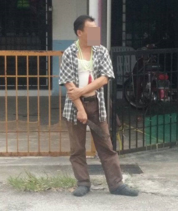 精神失常的华裔男子在住家前，手握巴冷刀与警方对峙。（警方提供照片