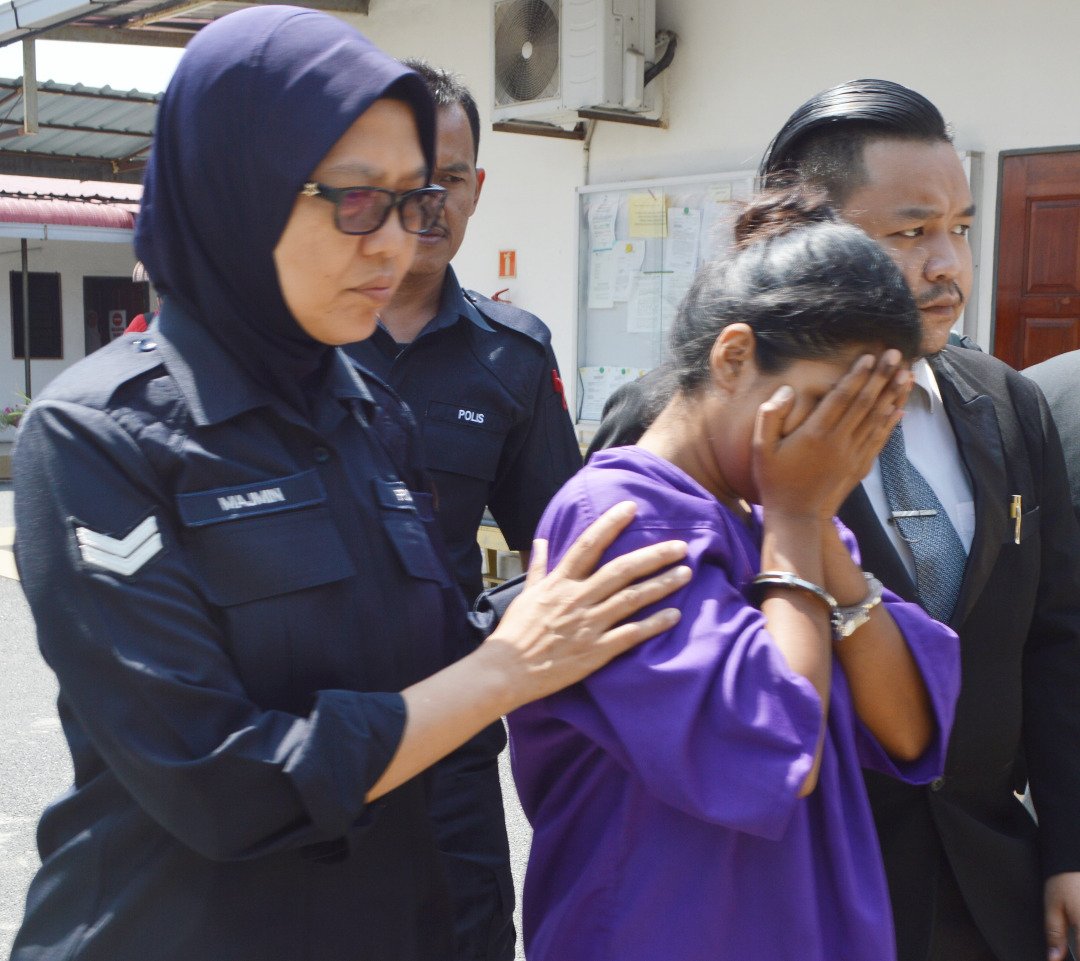 小死者31岁的母亲被警方押往法庭申请延扣时，以双手遮盖脸部。