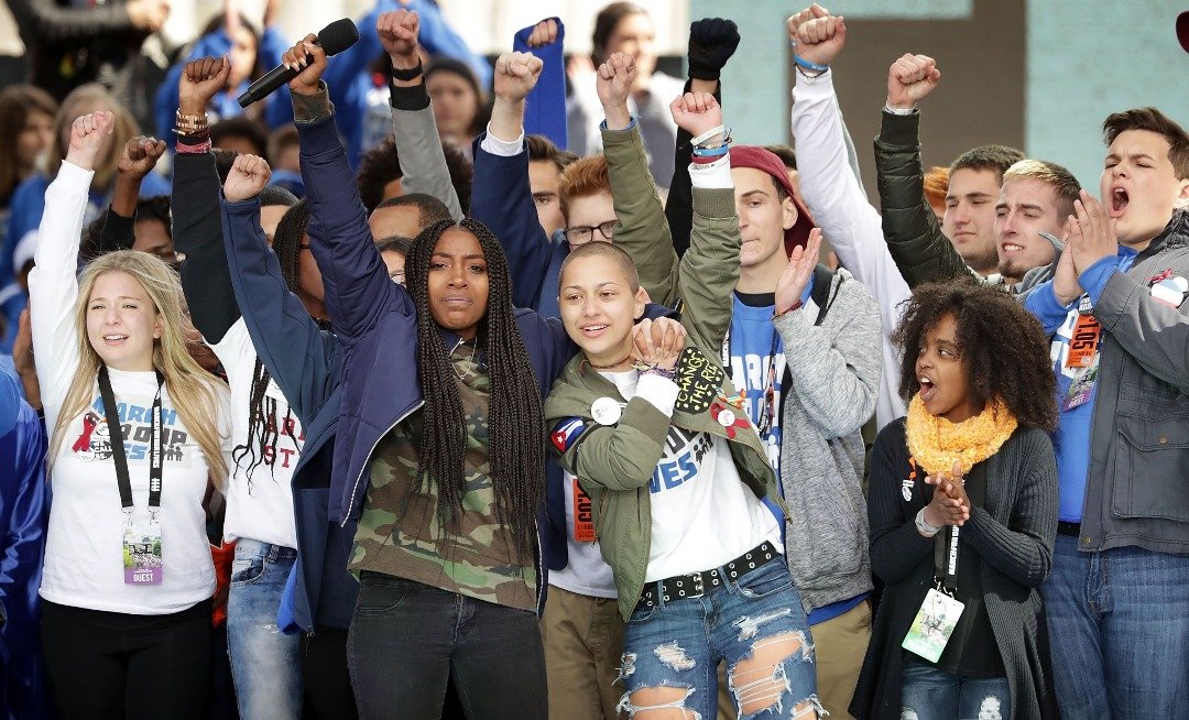 上个月在华盛顿举行的“为活命而走”全国反枪枝暴力集会上，帕克兰市玛乔丽·斯通曼·道格拉斯高中的学生，在台上高举拳头，反对枪支暴力。