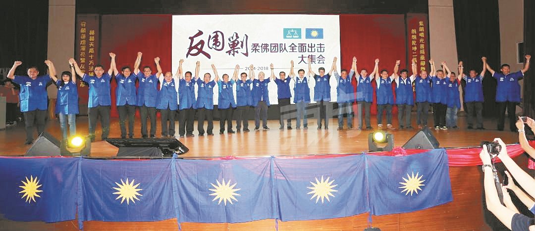 马华柔州候选人穿上蓝色“战袍”与魏家祥（前排左11起）及廖中莱高举双手，充分展现马华已做好准备，迎战来届大选。（摄影：刘维杰）