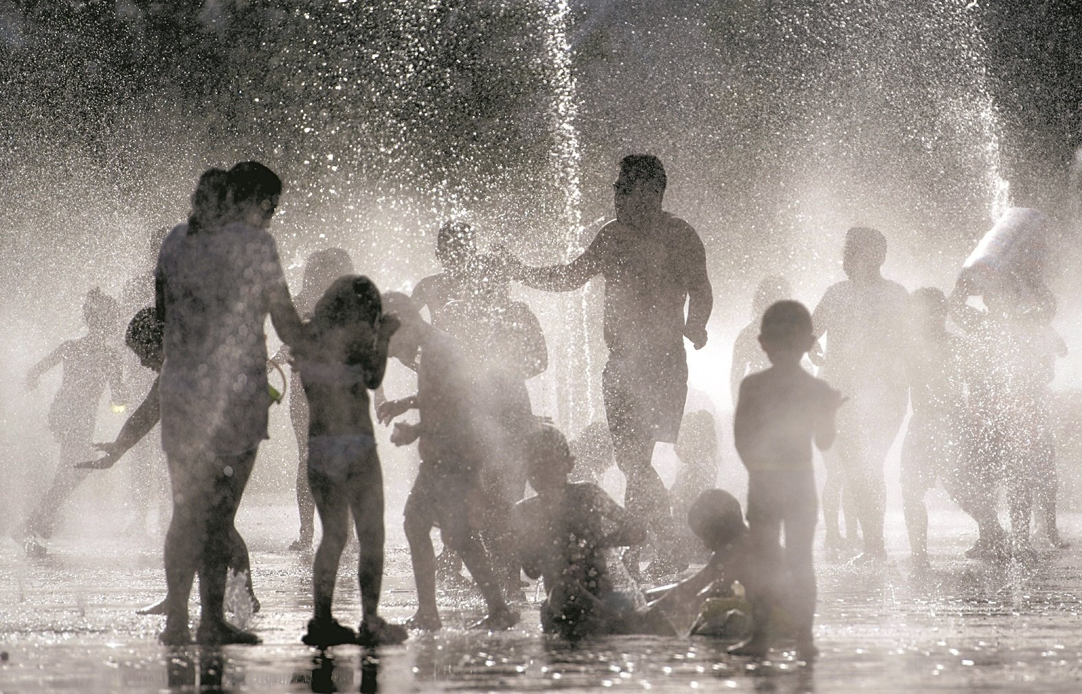 马德里近日出现大热天，曼萨纳雷斯河边的马德里里约公园，大人和小孩在喷泉内戏水消暑。