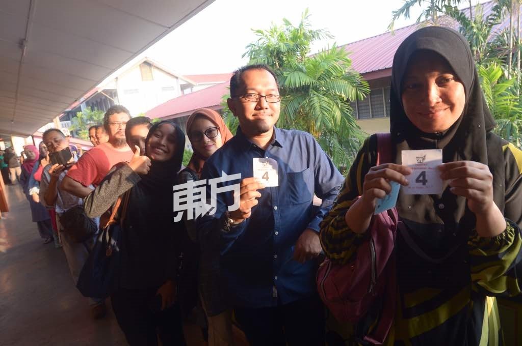 选民们站在投票室外排队，举起手中的4号投票室号码。（摄影：陈启新）