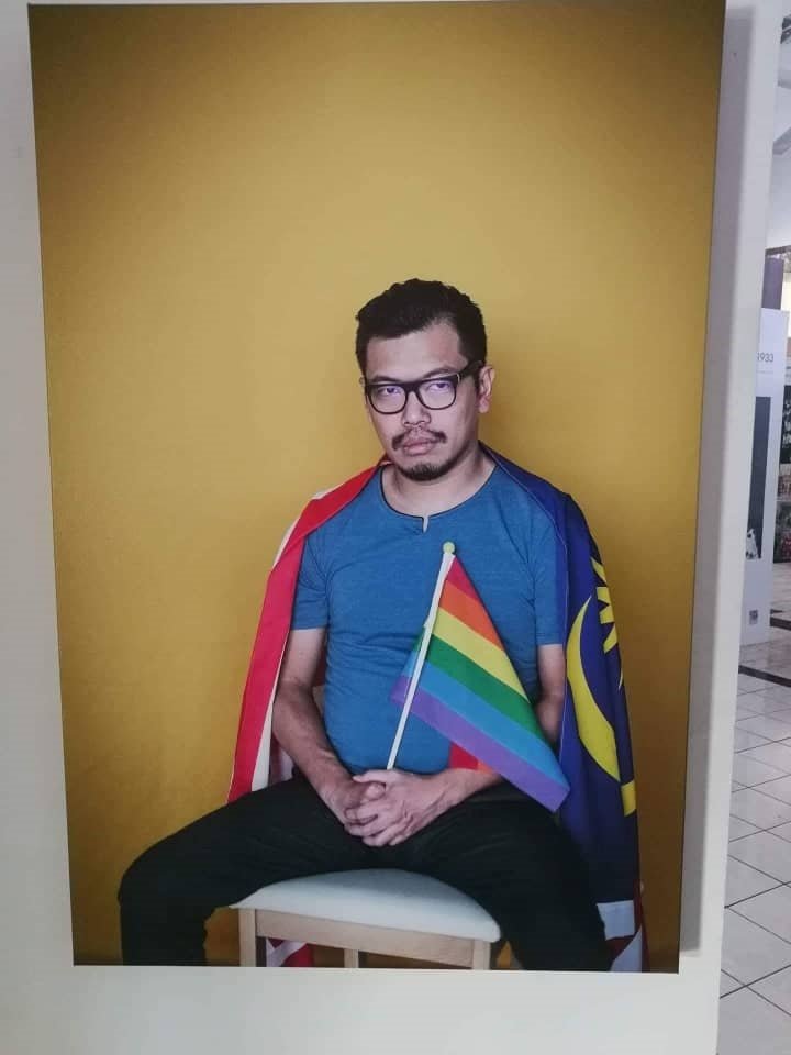 冯启德身挂国旗，手握代表“同性和双性恋及跨性别者”的彩虹旗，该肖像在摄影展上展出，因引起不满而被撤下。