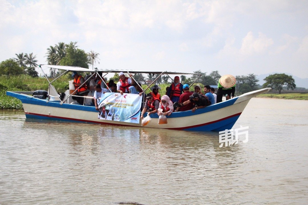 莫哈末峇迪亚（左起）和诺雷拉乘坐船只到北赖河中央放入鱼苗。