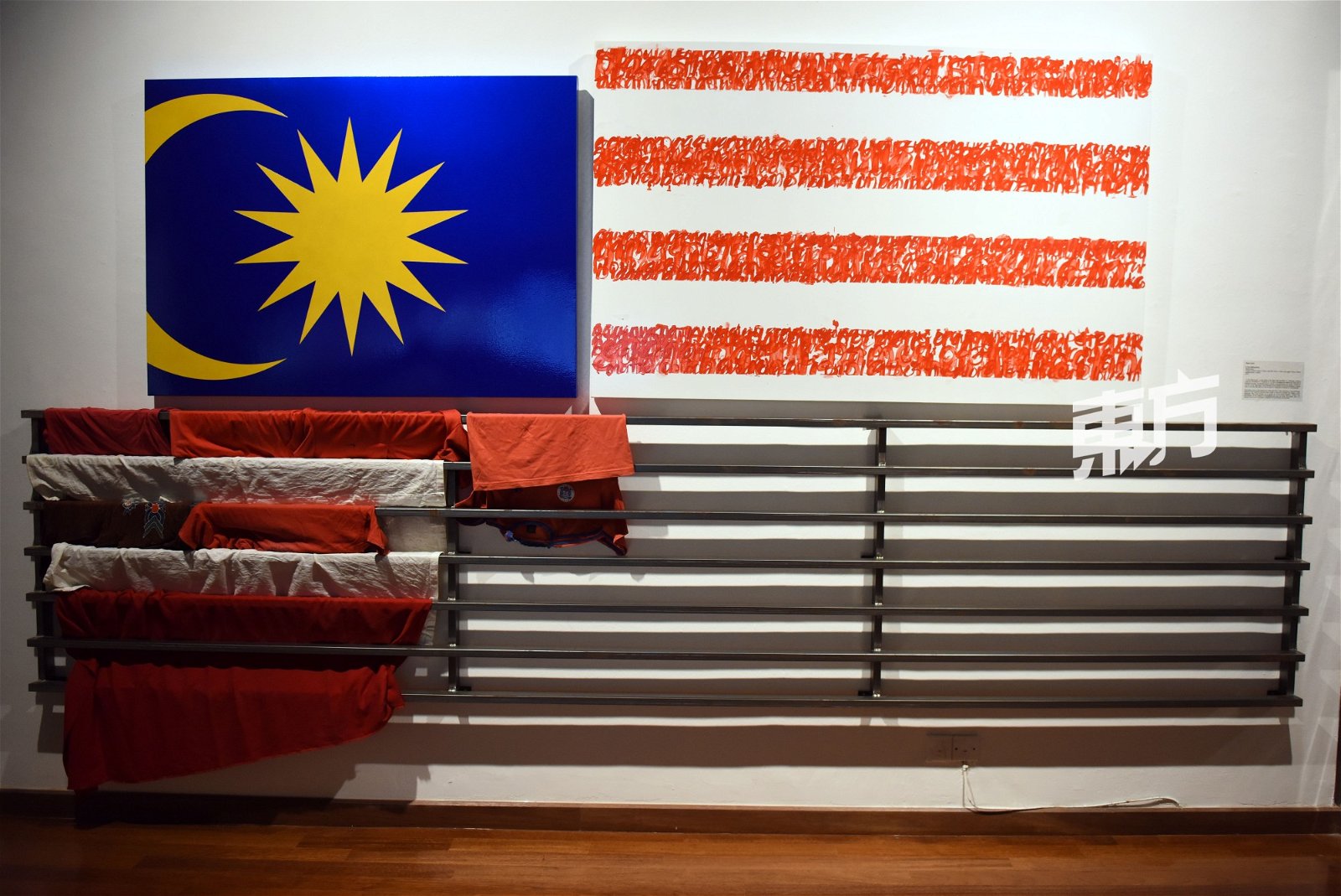 这是取名“A Few Malaysia(s)”的互动装置，作者Sean Lean邀请身穿红色或白色衣服的观展者把衣服留下，共同完成这面旗，惟，碍于观展者几乎都没有携带额外的衣服，所以作品目前仍处于未完成状态。