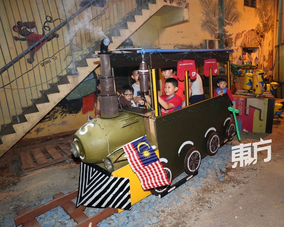 新增一图：孩子们在壁画前乘坐由再循环物品制成的火车游玩。（摄影：刘维杰）