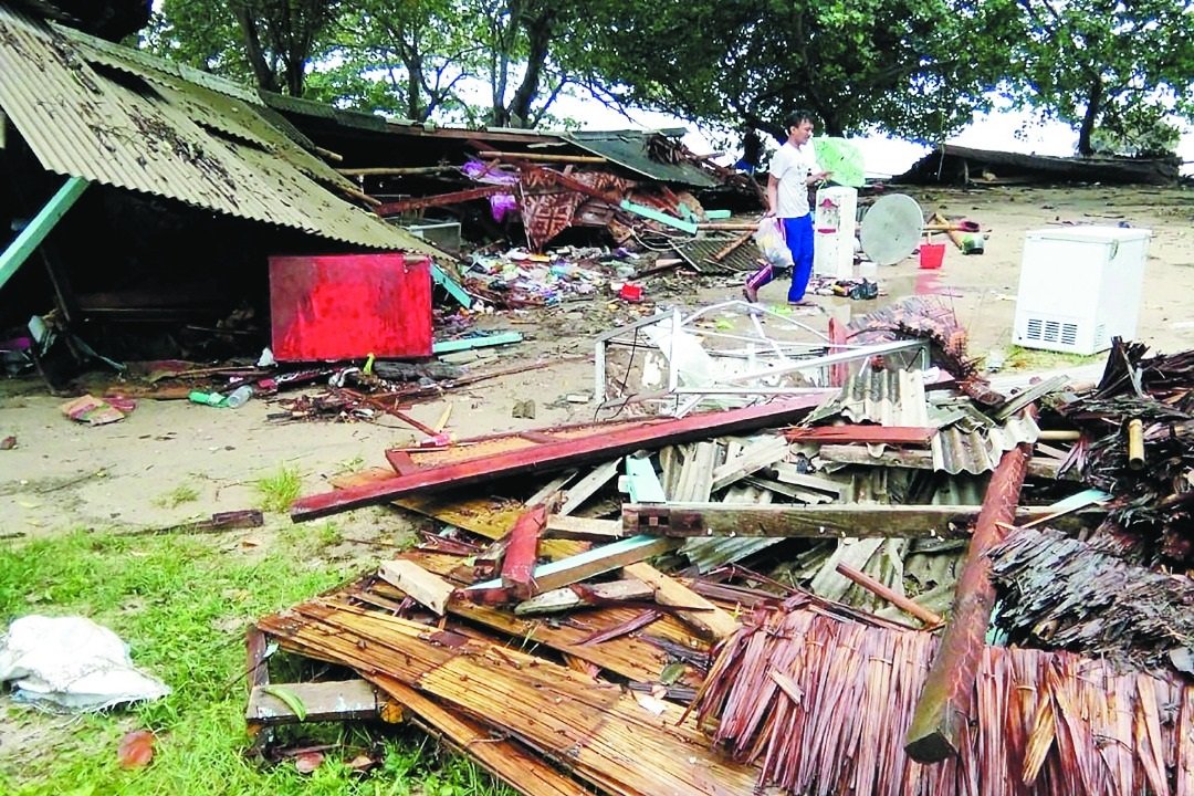 印尼巽他海峡周六晚发生海啸，沿海城镇受灾严重，图为在查丽达海滩，一名男子在倒塌房屋里寻找仍可使用的物品。