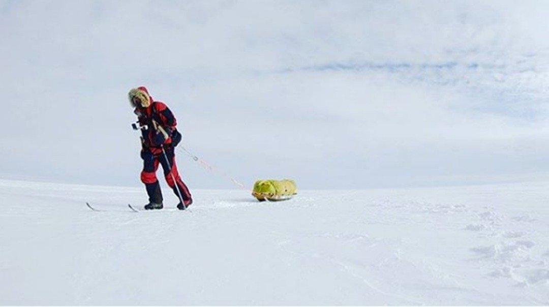奥布雷迪穿戴著厚重的御寒装备、手拄登山杖、尾拖著一个行李，在白皑皑的南极雪地中一步步向前行。