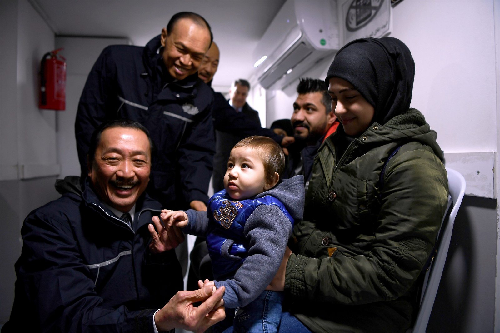 陈志远（左）和林伟才（左2）在探访一家免费诊所时，他们逗弄一名只有11个月大的叙利亚难民，并捐助物资。