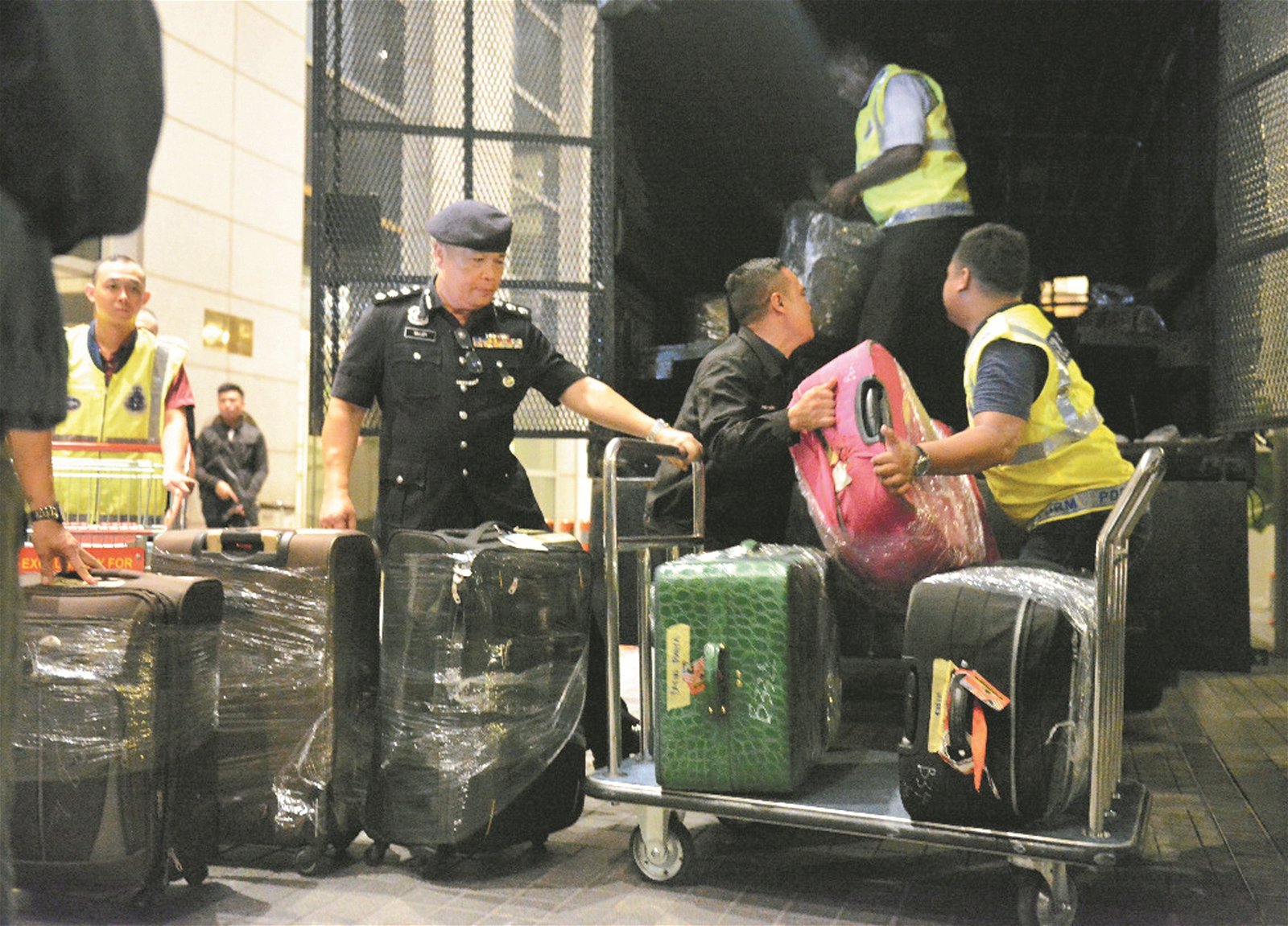 警方在搜查纳吉行动中，将装有大笔现款、 珠宝、金饰及名表等财物的行李箱搬上车。
