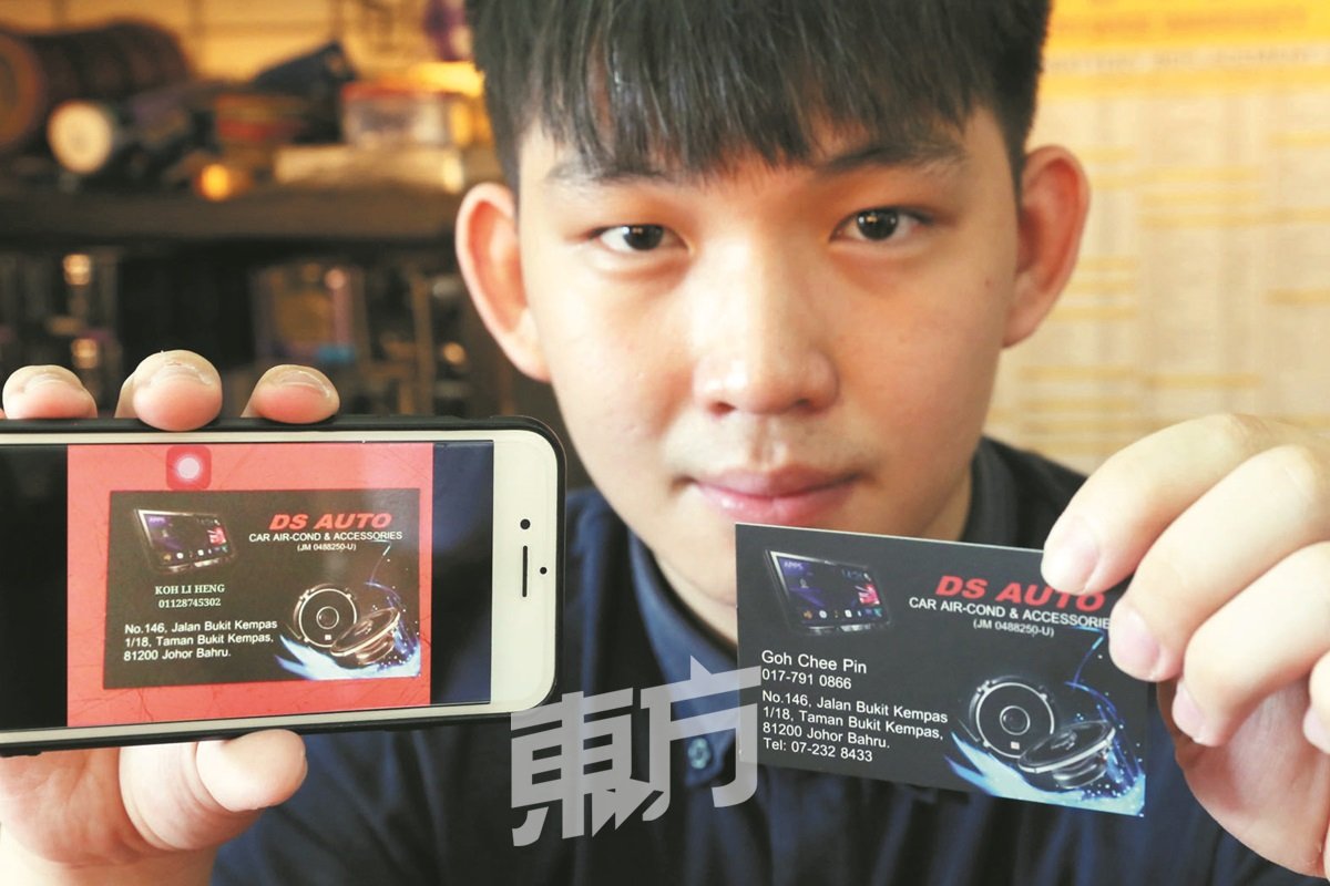 吴启彬用手机展示冒名者修改后的名片，与该店真实名片对比差异。（摄影：刘维杰）