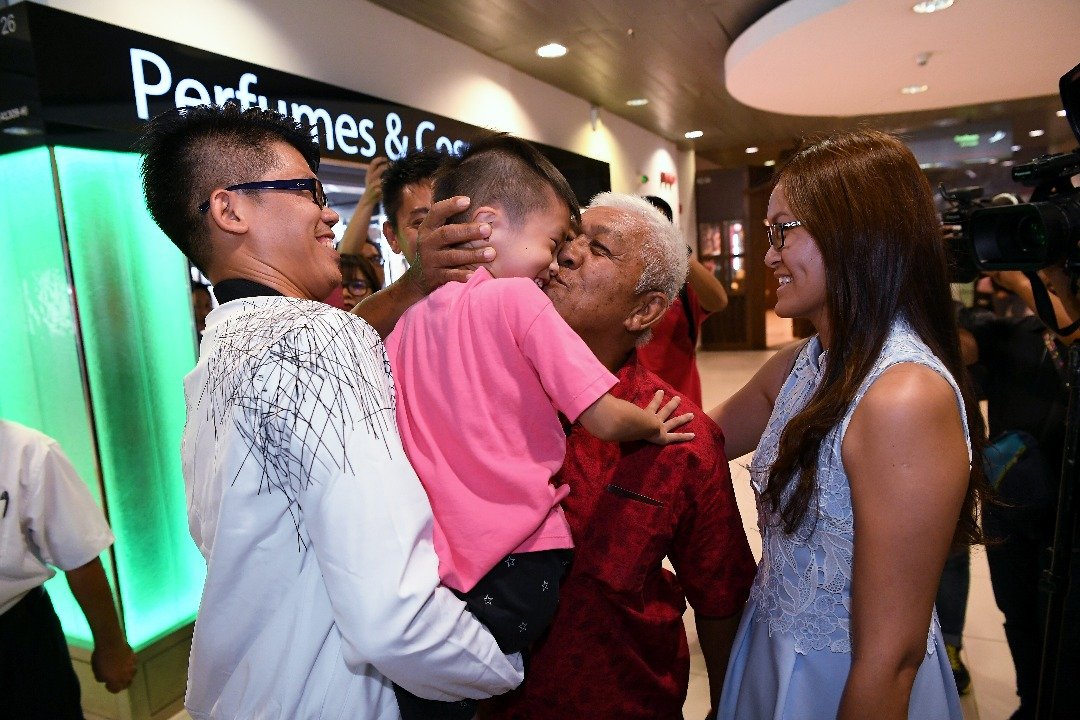 卢祥发（右2）抵达梳邦苏丹阿都阿兹沙机场时，兴奋的抱起前来接机的孙子邓江翰（译音），并亲吻他的脸颊。