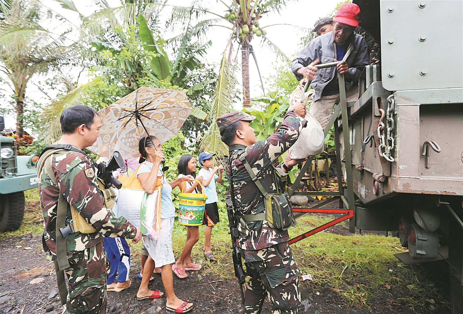 在阿尔拜省的巴东镇，菲律宾军人协助居民乘搭军用卡车，前往临时收容中心。
