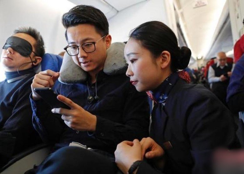 空姐向旅客讲解如何在飞行模式下正确使用手机。